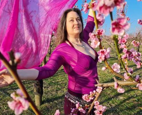 Iris tanzt mit pinken Schleier in rosa Nektarinnenblüten