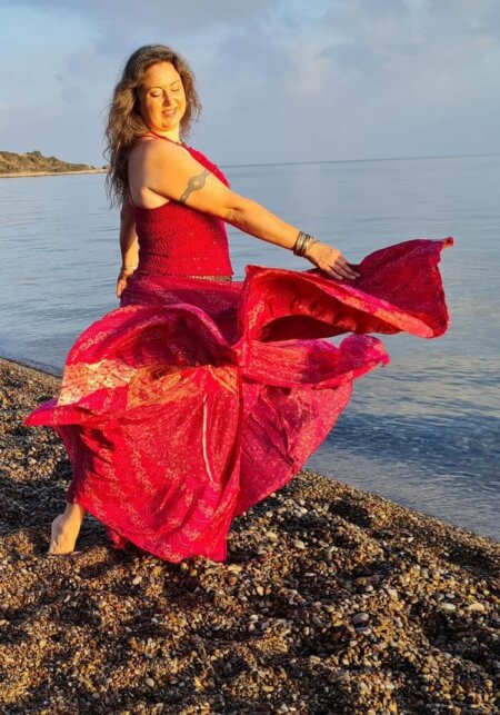 Iris tanzt am Meer und blickt auf ihren mit pinken Tellerrock