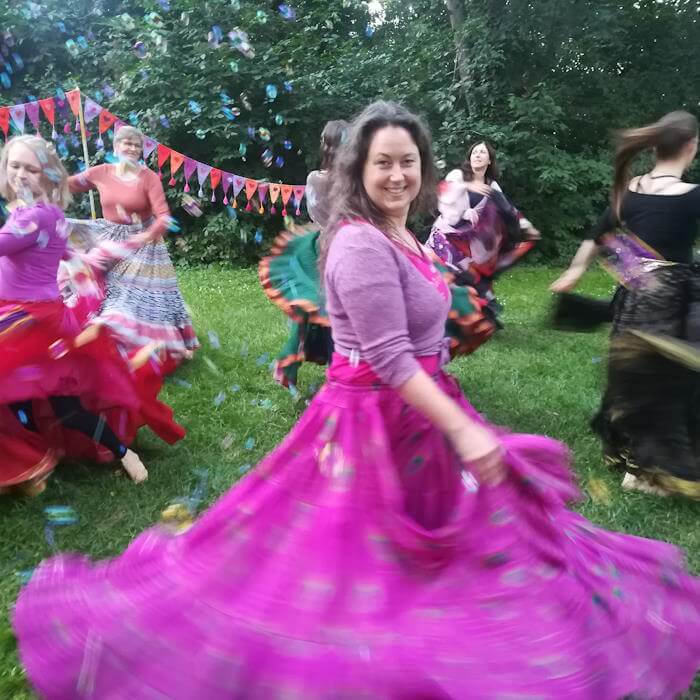 Tanzende Frauen mit bunten Tellerröcken auf der Wiese und Seifenblasen