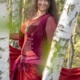 Iris lachend mit rotem Kleid zwischen Birkenstämmen im Wald