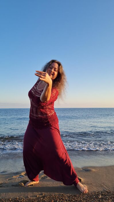 Iris tanzt in roter Kleidung am Strand