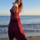 Iris tanzt in roter Kleidung am Strand