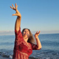 Iris tanzt in roter Kleidung am Strand